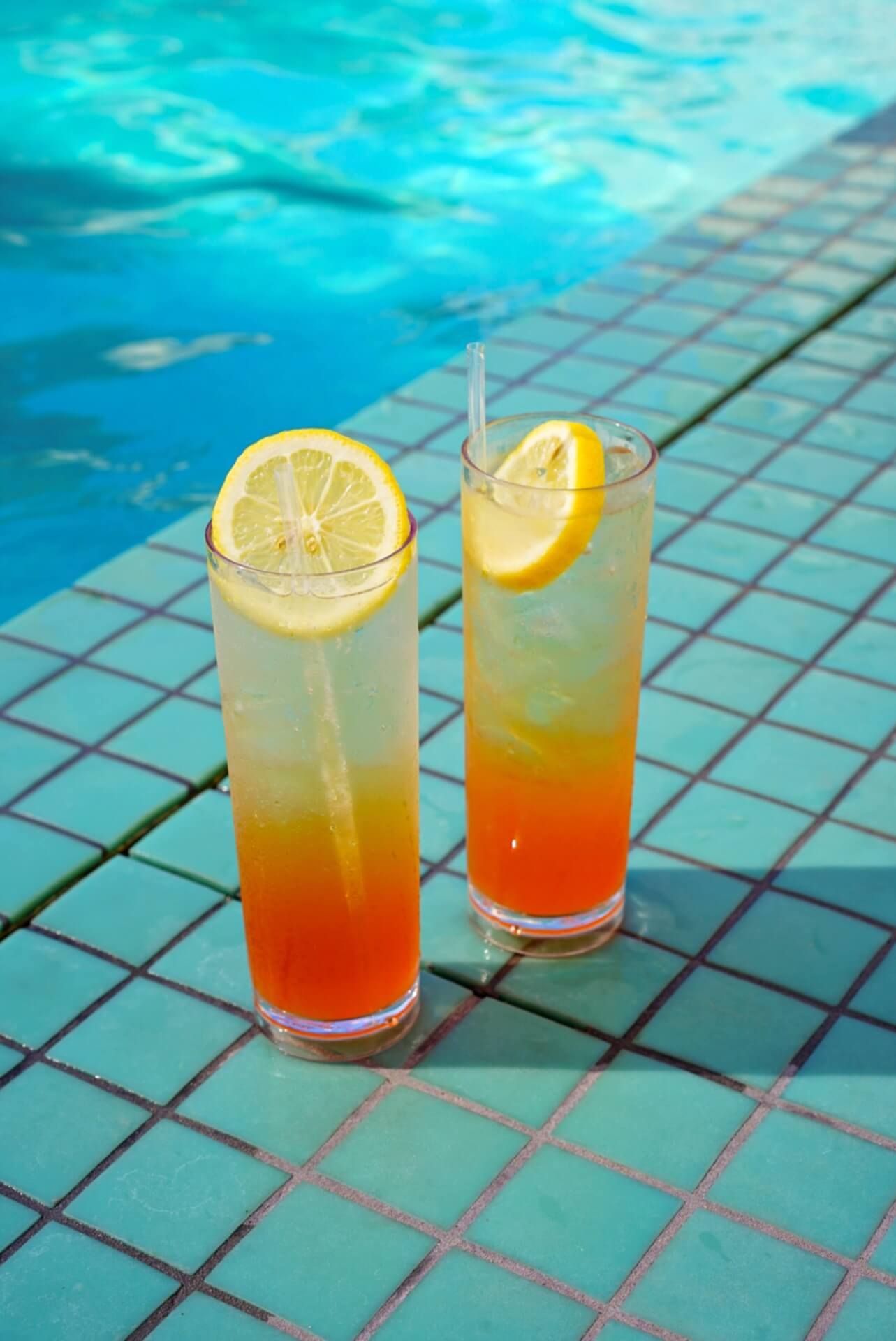 Zwei leckere Cocktails stehen am Rande eines Hotelpools