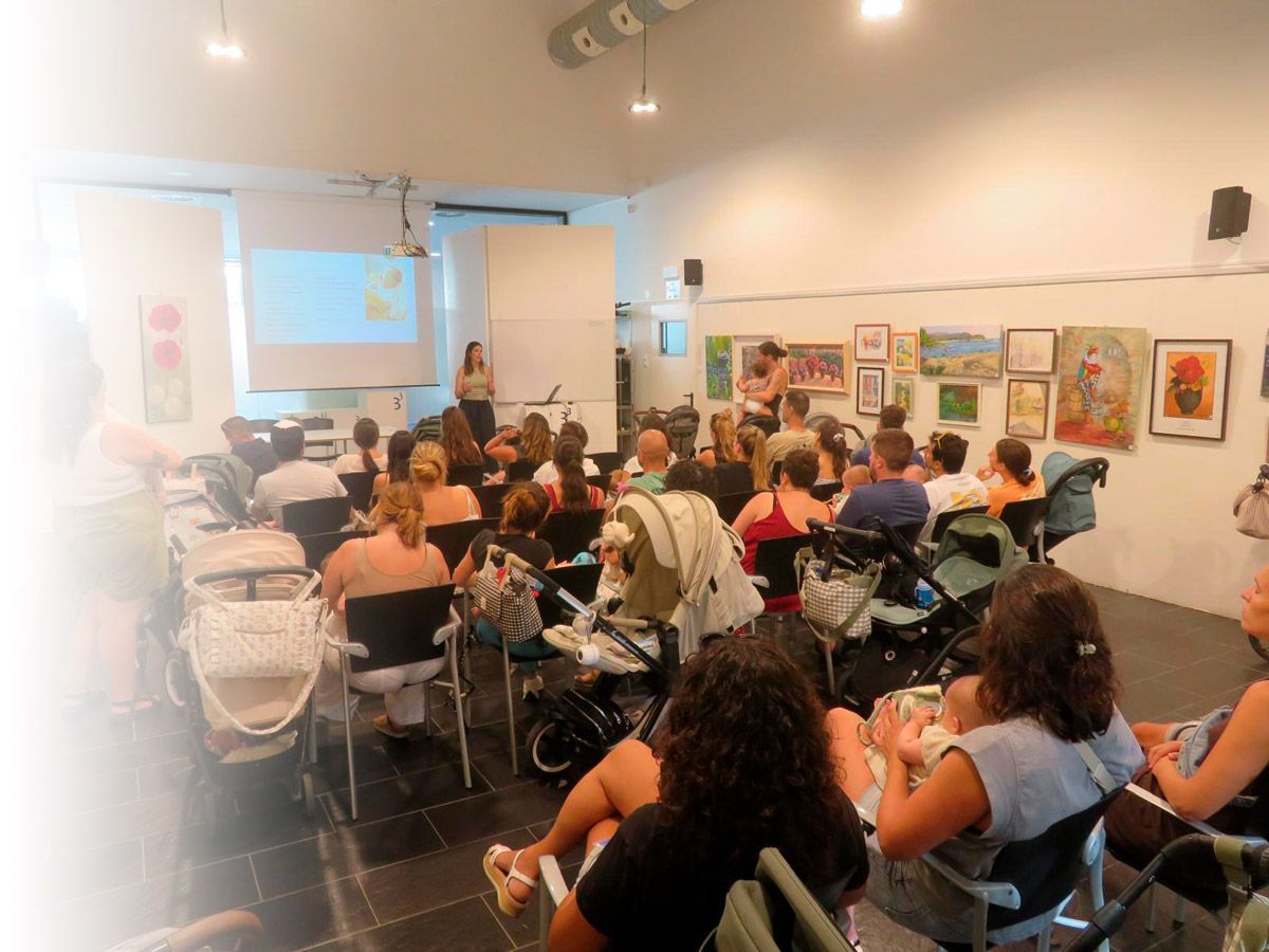 Personas sentadas en un aula de una galería de arte observando una presentación en una pantalla proyectada.