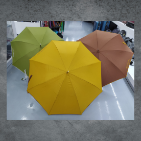 Tres paraguas de diferentes colores están sobre un suelo de hormigón.