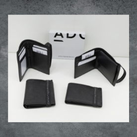 Hay tres carteras negras sobre una mesa junto a una caja que dice auc