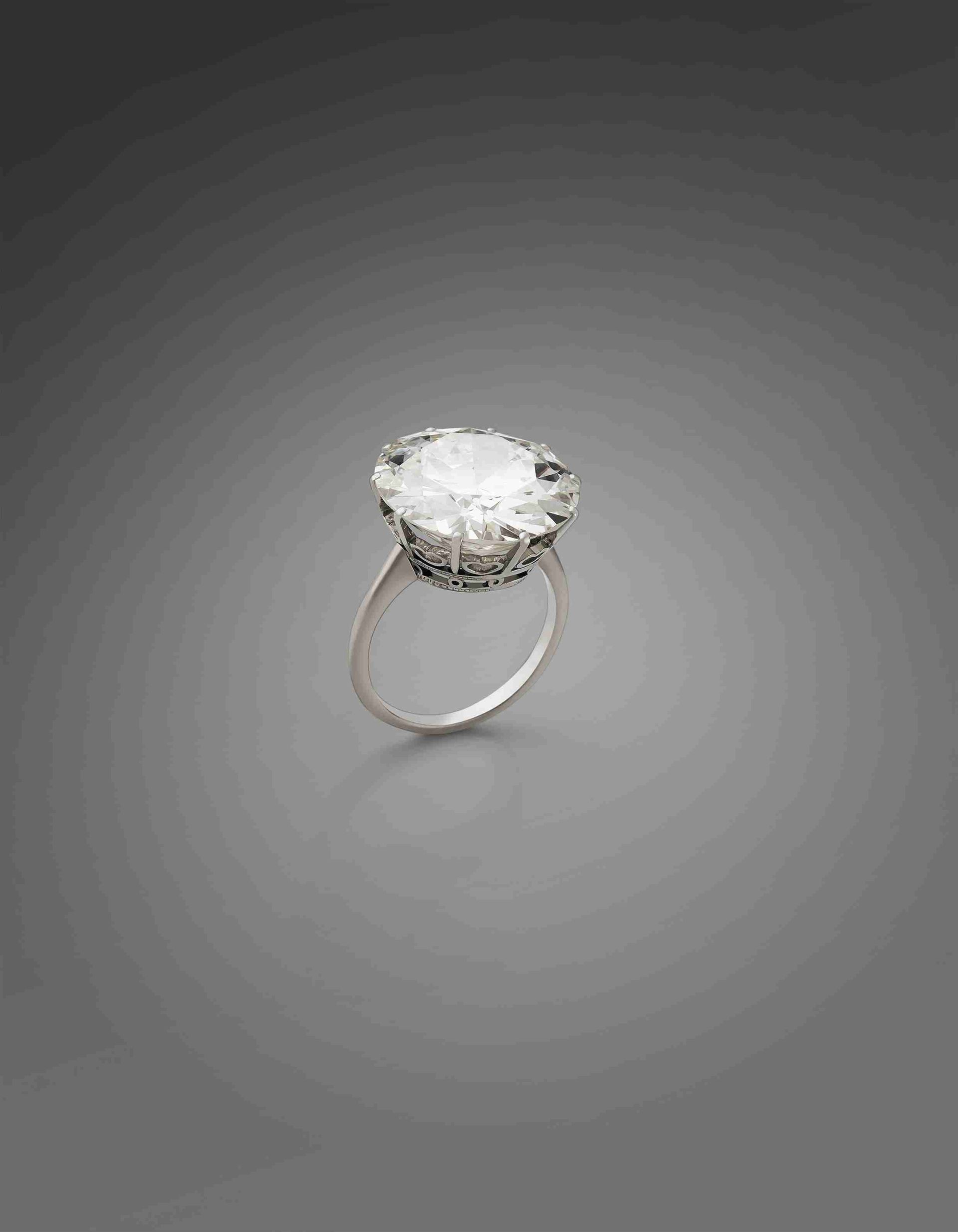 Bague en argent avec une grosse pierre claire entourée de pierres plus petites sur fond gris