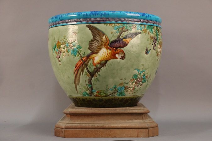 Pot en céramique à motif perroquet, bord bleu, sur un socle en bois