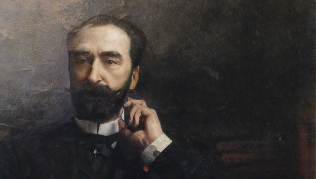 Portrait d'un homme avec une barbe, un costume sombre et un col blanc, touchant son visage