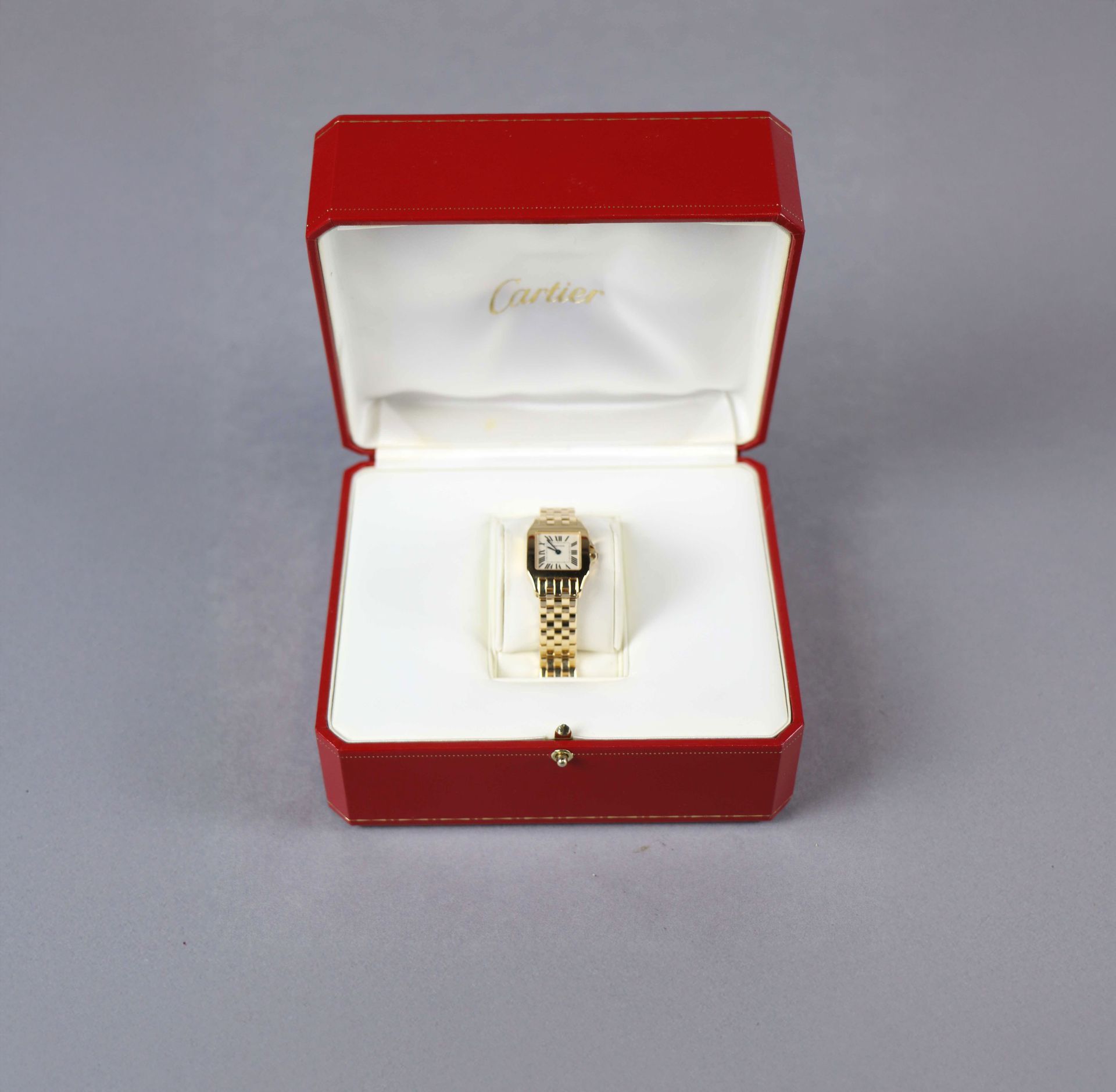 Coffret de montre Cartier rouge ouvert, montre en or à l'intérieur