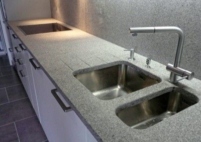 Évier de cuisine en acier inoxydable avec trois bacs et un long plan de travail.