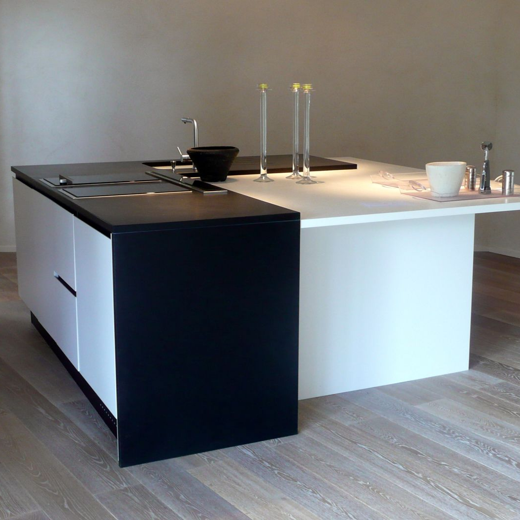 Un îlot de cuisine minimaliste comprenant un plan de travail noir avec une plaque de cuisson.