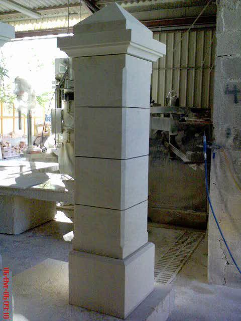 Grande colonne ou pilier en pierre dans un atelier, partiellement sculpté et orné de marques.