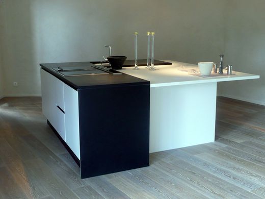 Îlot de cuisine moderne avec meubles noirs et blancs dans une pièce vide
