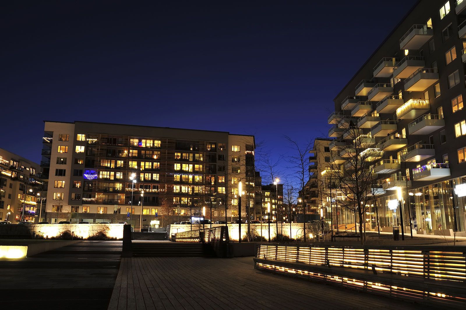Les bâtiments de la ville illuminés au crépuscule ; un ciel bleu foncé au-dessus.