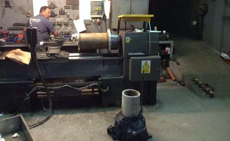 Un hombre está trabajando en un torno en un garaje.