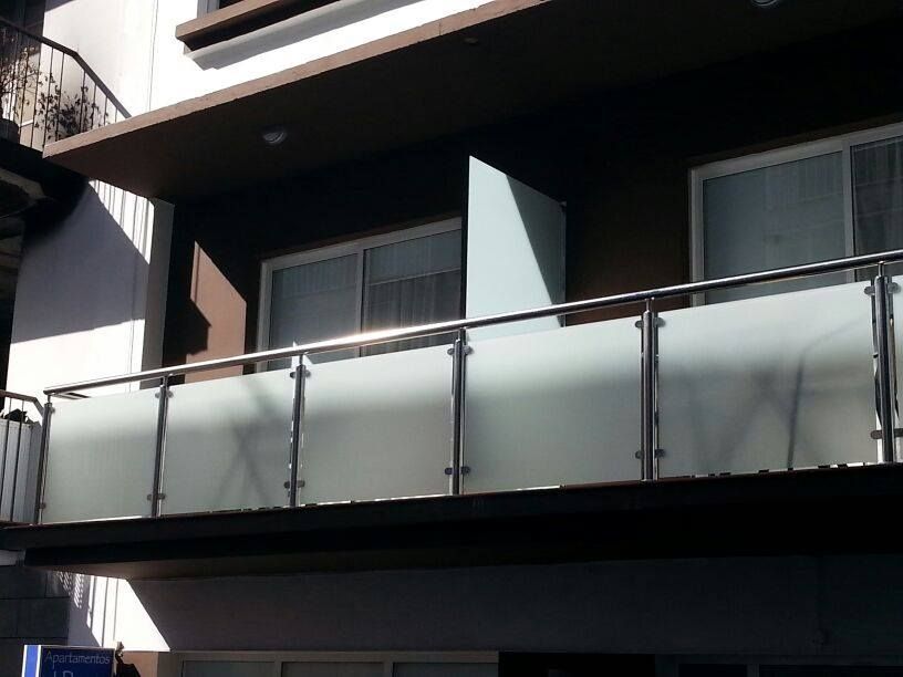 Un balcón con barandilla de acero inoxidable y vidrio esmerilado.