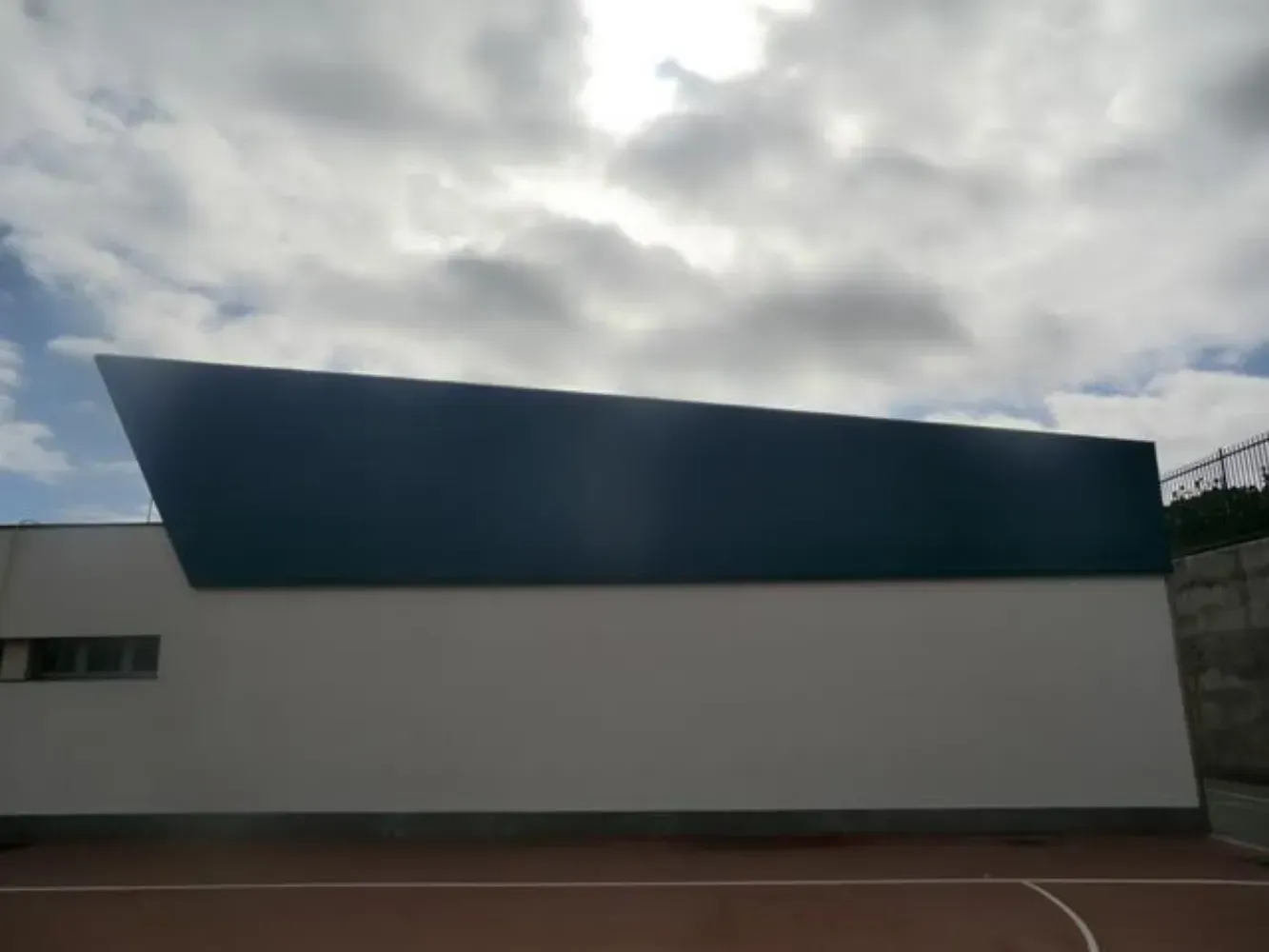 Un edificio azul y blanco con una cancha de baloncesto enfrente.