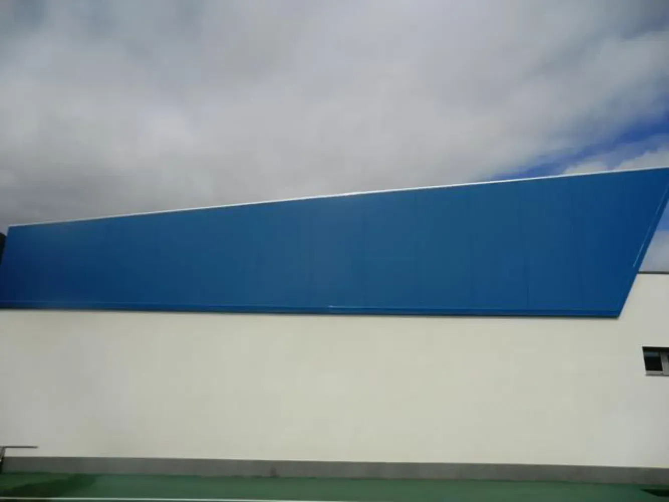 Un edificio azul y blanco con un cielo nublado al fondo.