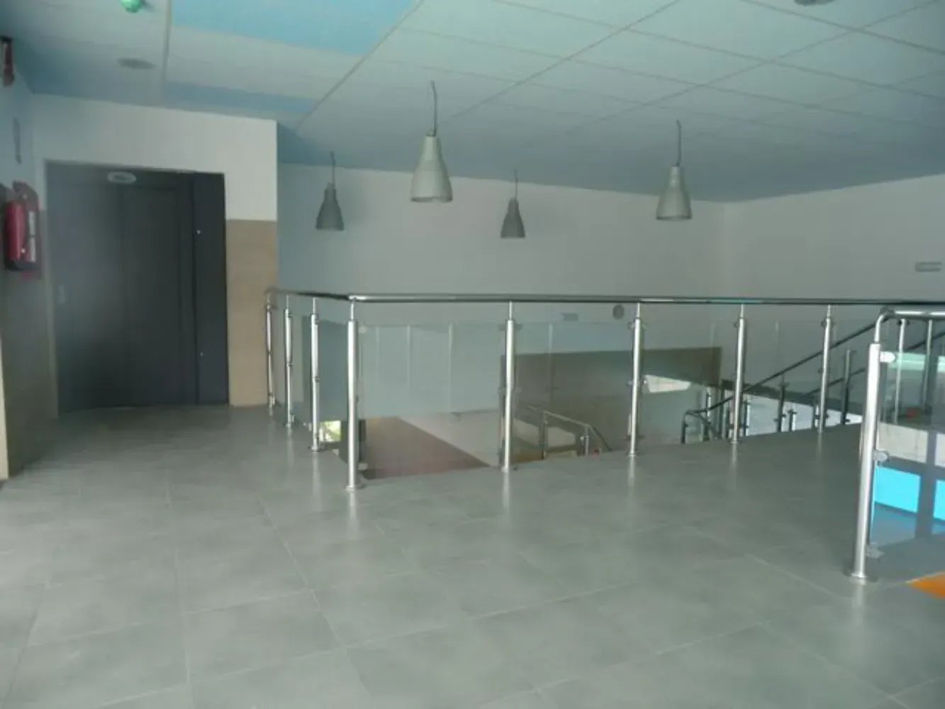 Una habitación vacía con escaleras y una barandilla de cristal.