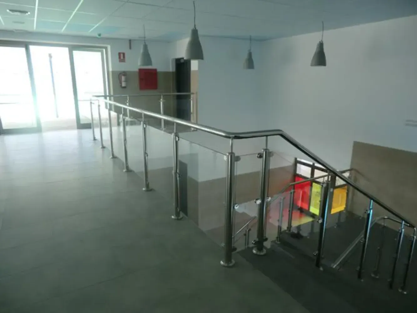 Una escalera con barandilla de cristal y una vidriera.