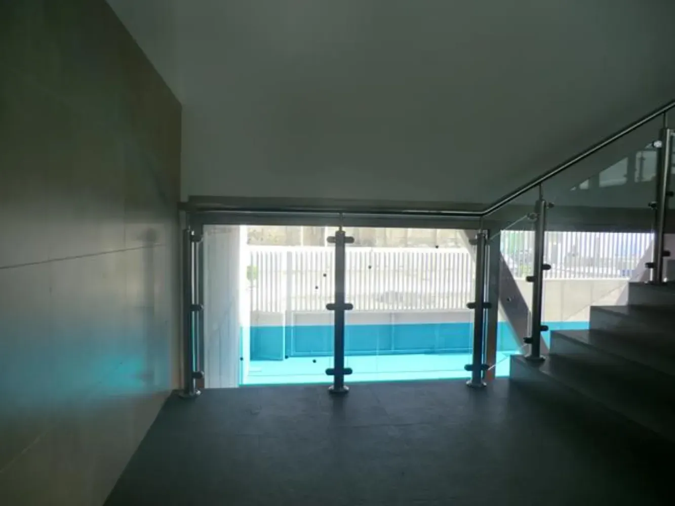 Una escalera con barandilla de cristal que conduce a una piscina.