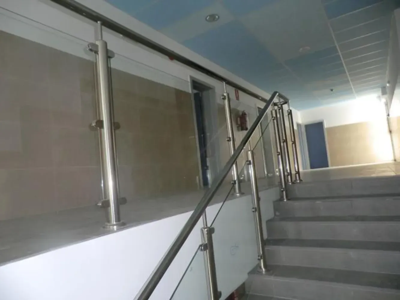 Una escalera con barandilla de acero inoxidable y barandilla de vidrio.