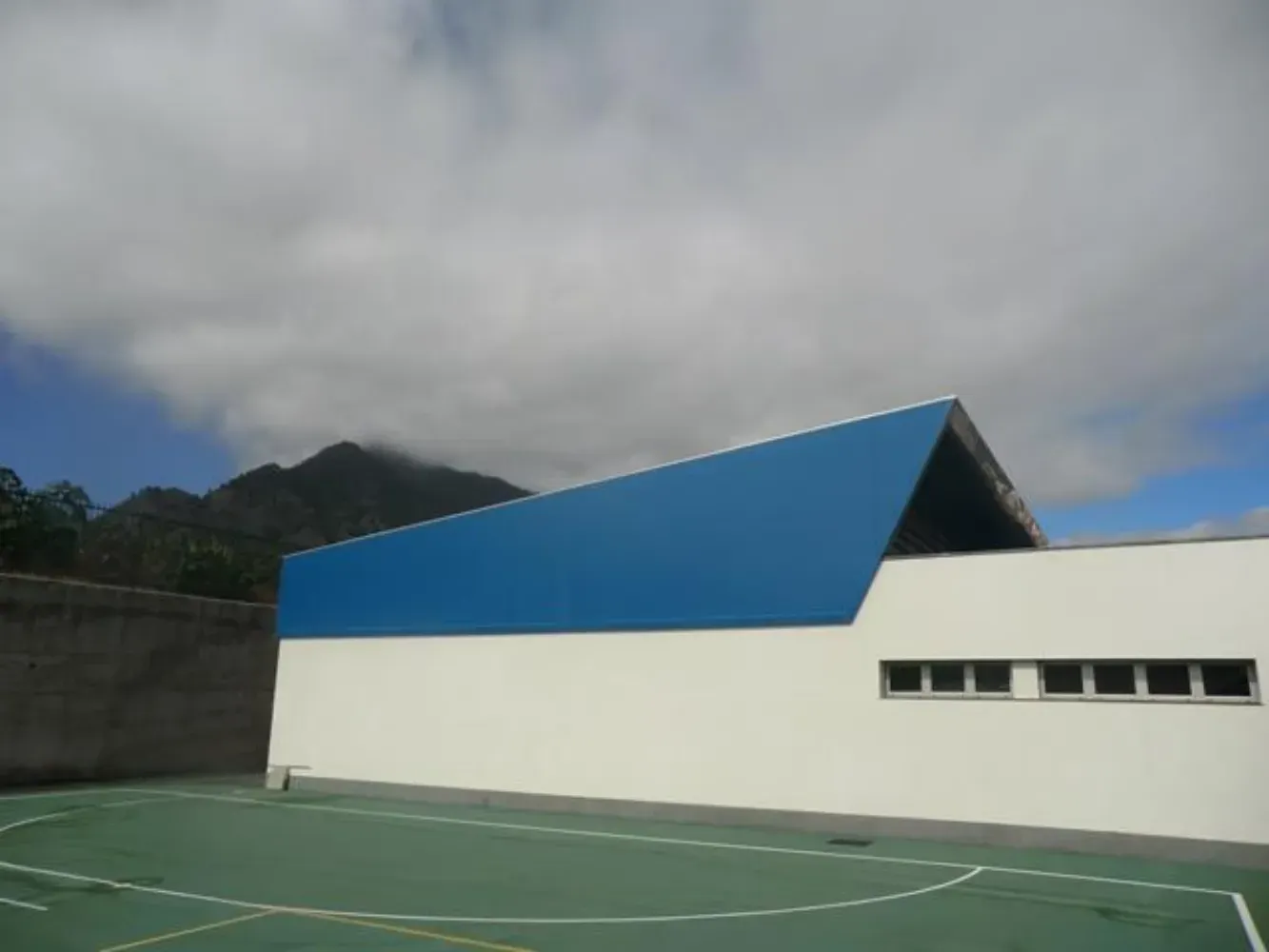 Un edificio azul y blanco con una cancha de baloncesto enfrente.