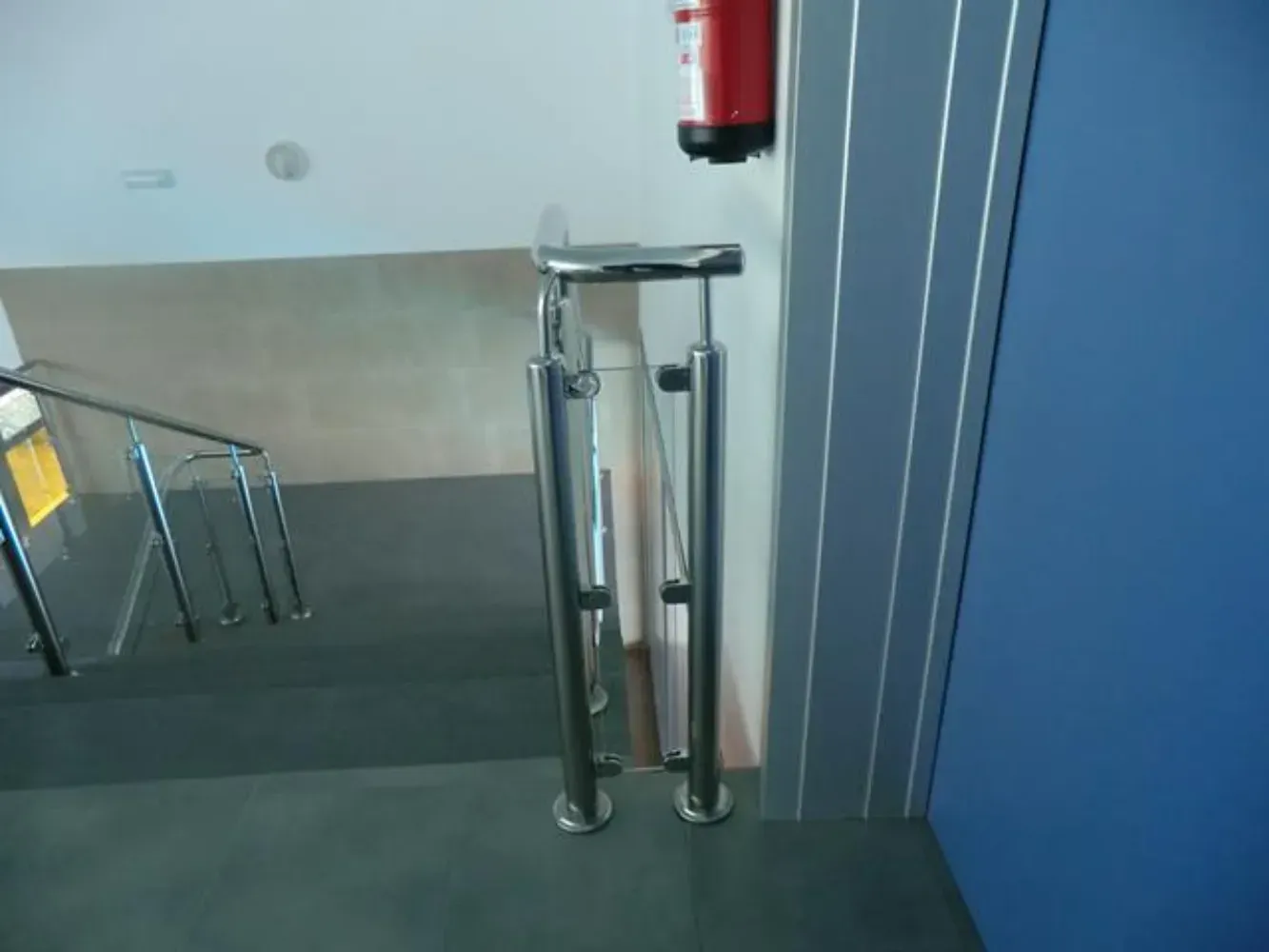 Un extintor de incendios está colgado en una pared junto a unas escaleras.