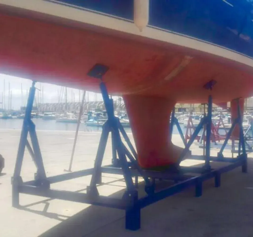 Un barco está en un soporte en un puerto deportivo.