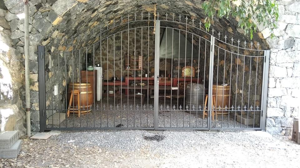 Una puerta de hierro forjado rodea una cueva con barriles en su interior.