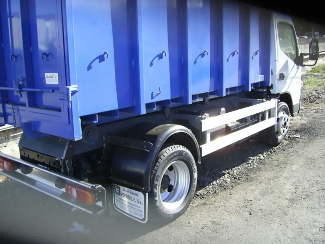 Un camión volquete azul está estacionado al costado de la carretera