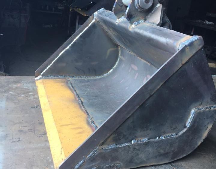 Un cubo de metal está sobre una superficie de hormigón.