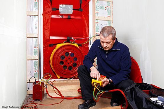 Handwerker sitzt vor einer Anlage