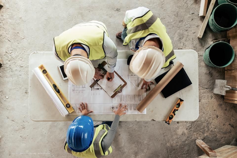 Arndt Bau Bauunternehmung GmbH – drei Bauarbeiter gehen über Notizen und Blaupausen