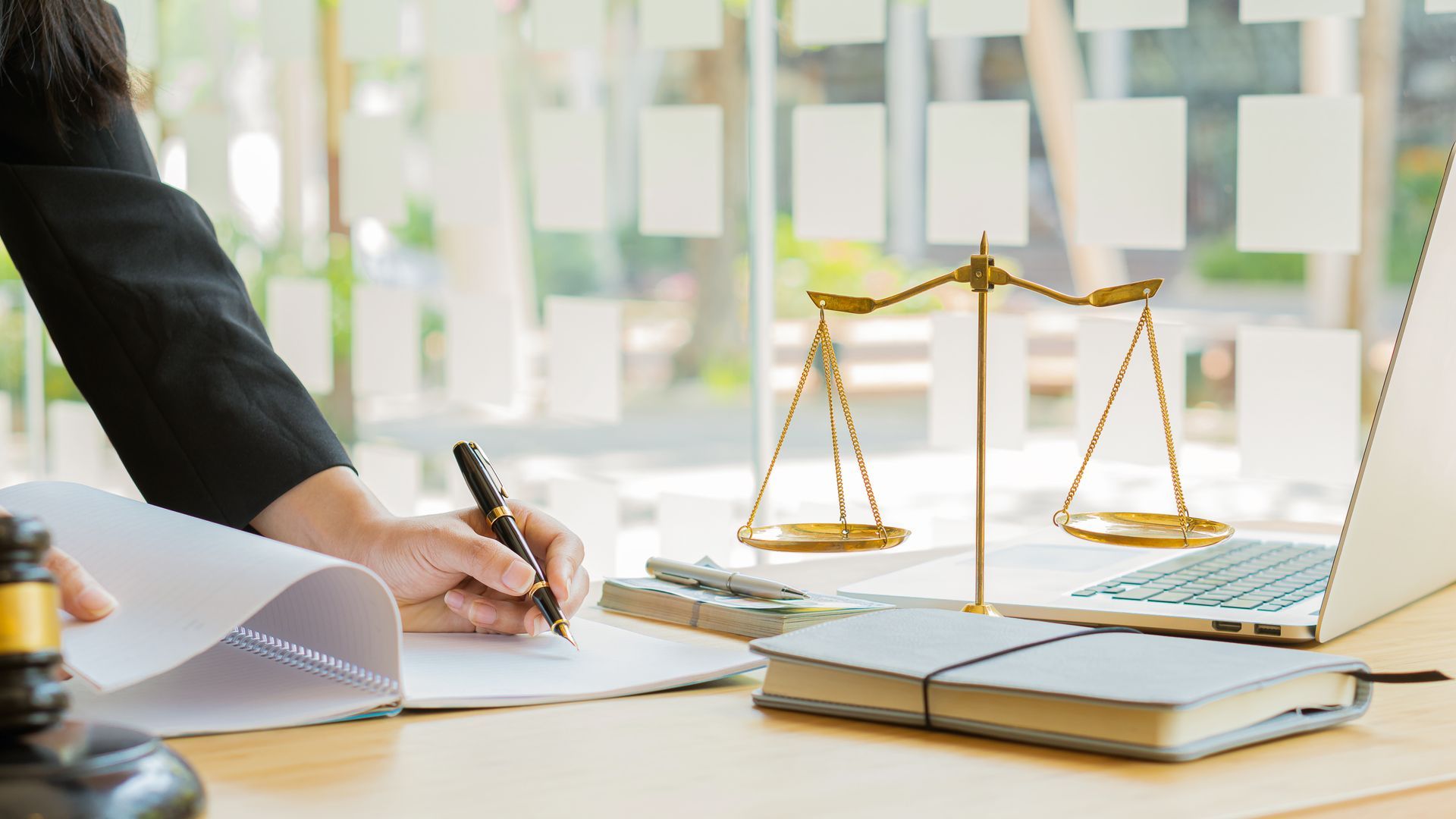 Une personne tenant un stylo devant le symbole de la justice.
