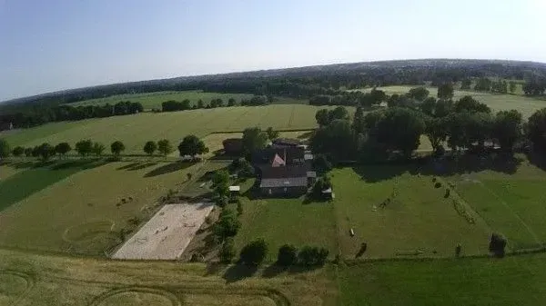 eine Luftaufnahme eines Bauernhofs mit einem Haus inmitten eines Feldes.