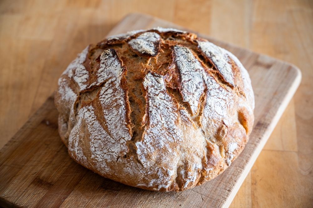 Pan redondo y crujiente sobre una tabla de cortar de madera, espolvoreado con harina.