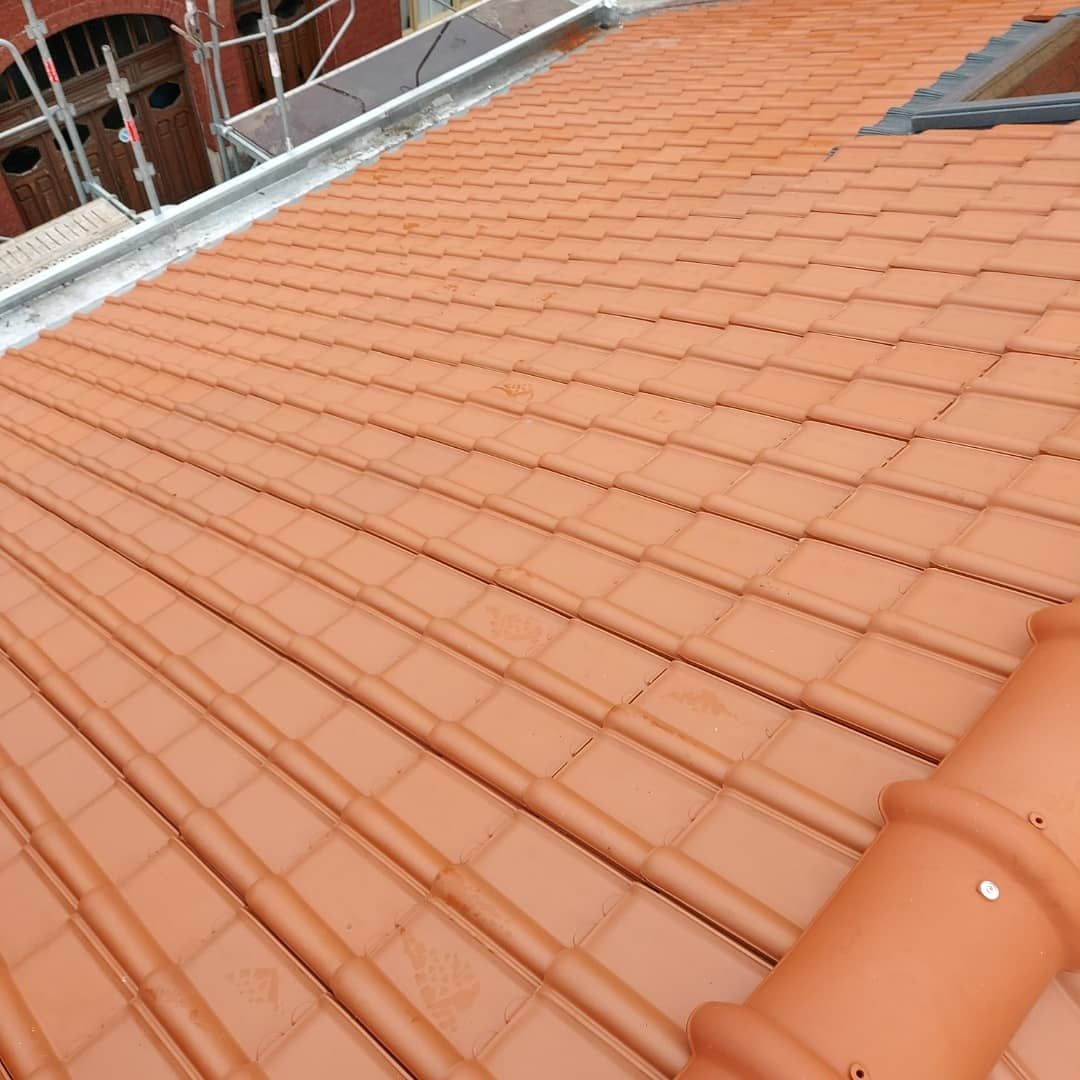 Toiture en tuiles rouges avec une canalisation et un puits de lumière, vue de dessus.