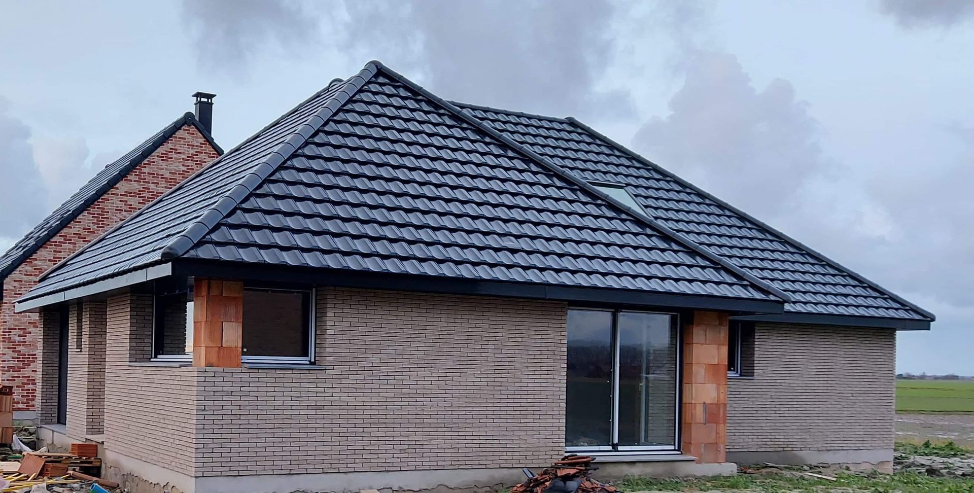 Gouttière grise avec des supports incurvés, fixée à un bâtiment en briques et en béton.