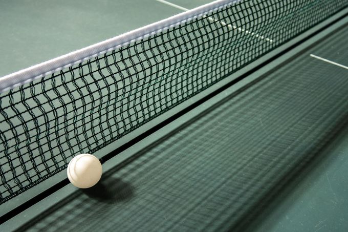 Ein Tischtennisball liegt am Rand des Netzes