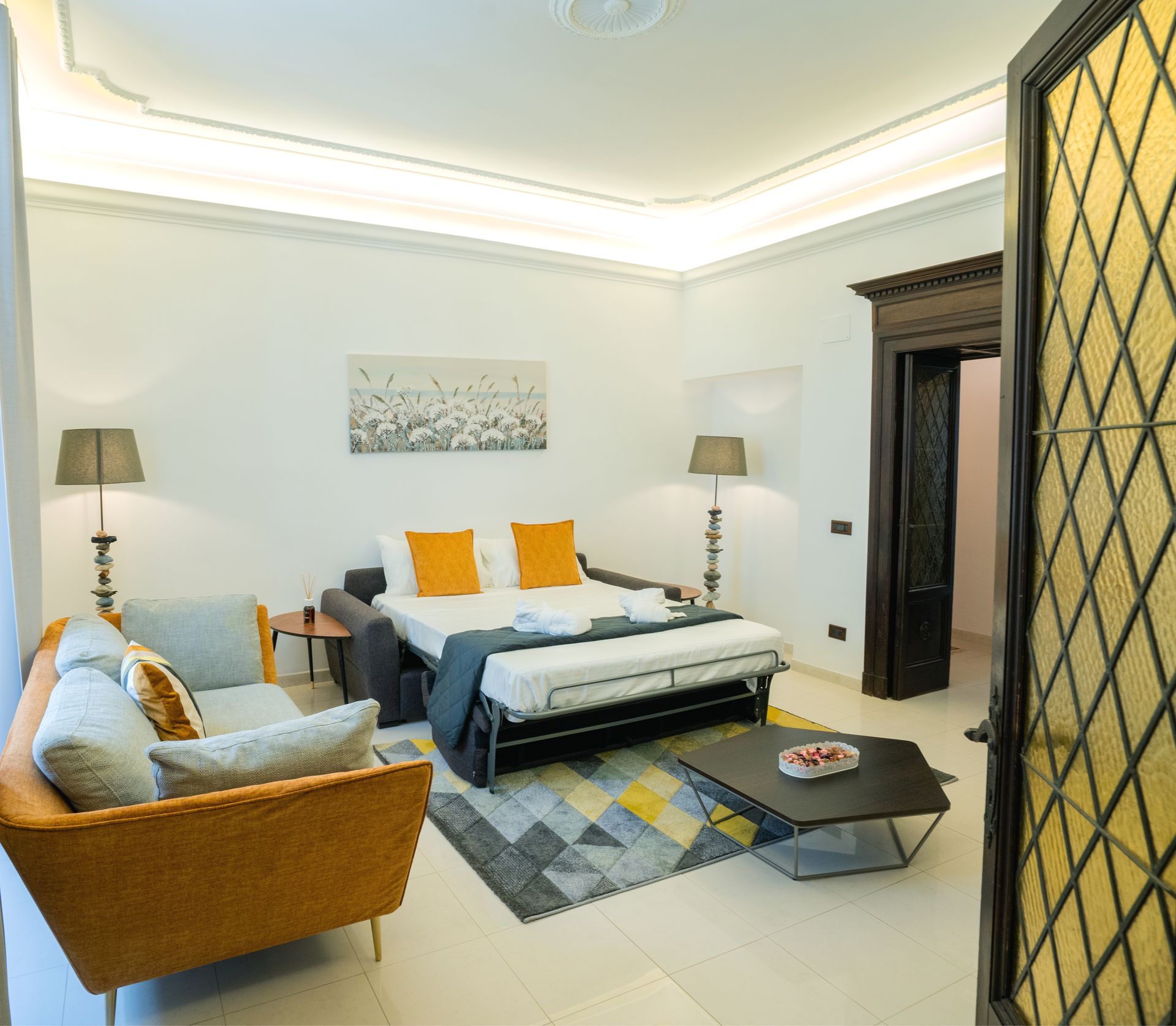 Cozy living space with a sofa bed, armchairs, coffee table, and a dark door.