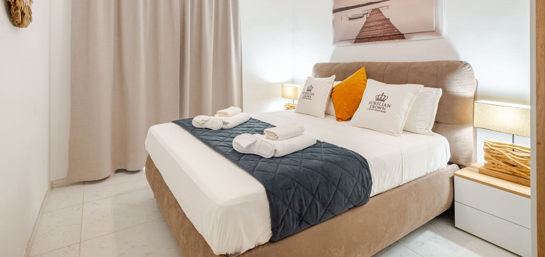 Bedroom with a bed covered in white linens, blue blanket, and two white towels.