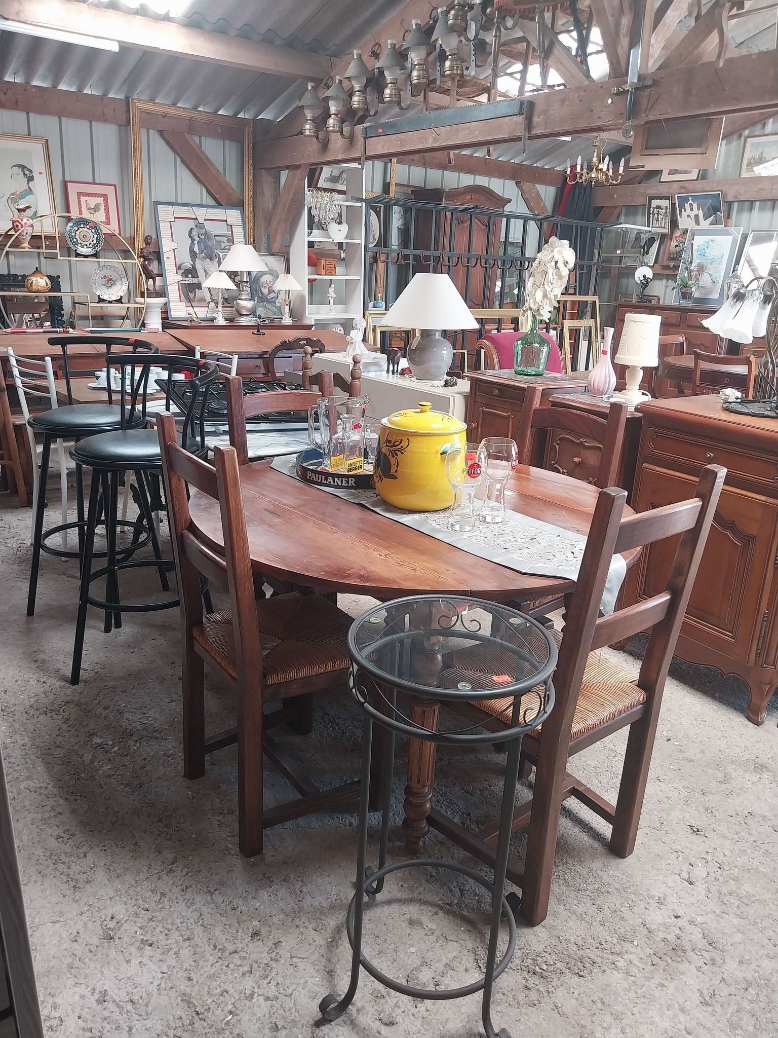 Intérieur d'une boutique d'antiquités, rempli de meubles, de lampes et de décorations. Table et chaises en bois en vedette.