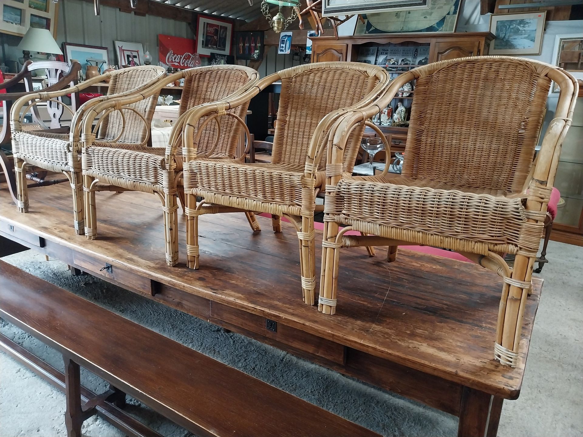 Quatre fauteuils en osier sur une table en bois, décor intérieur.