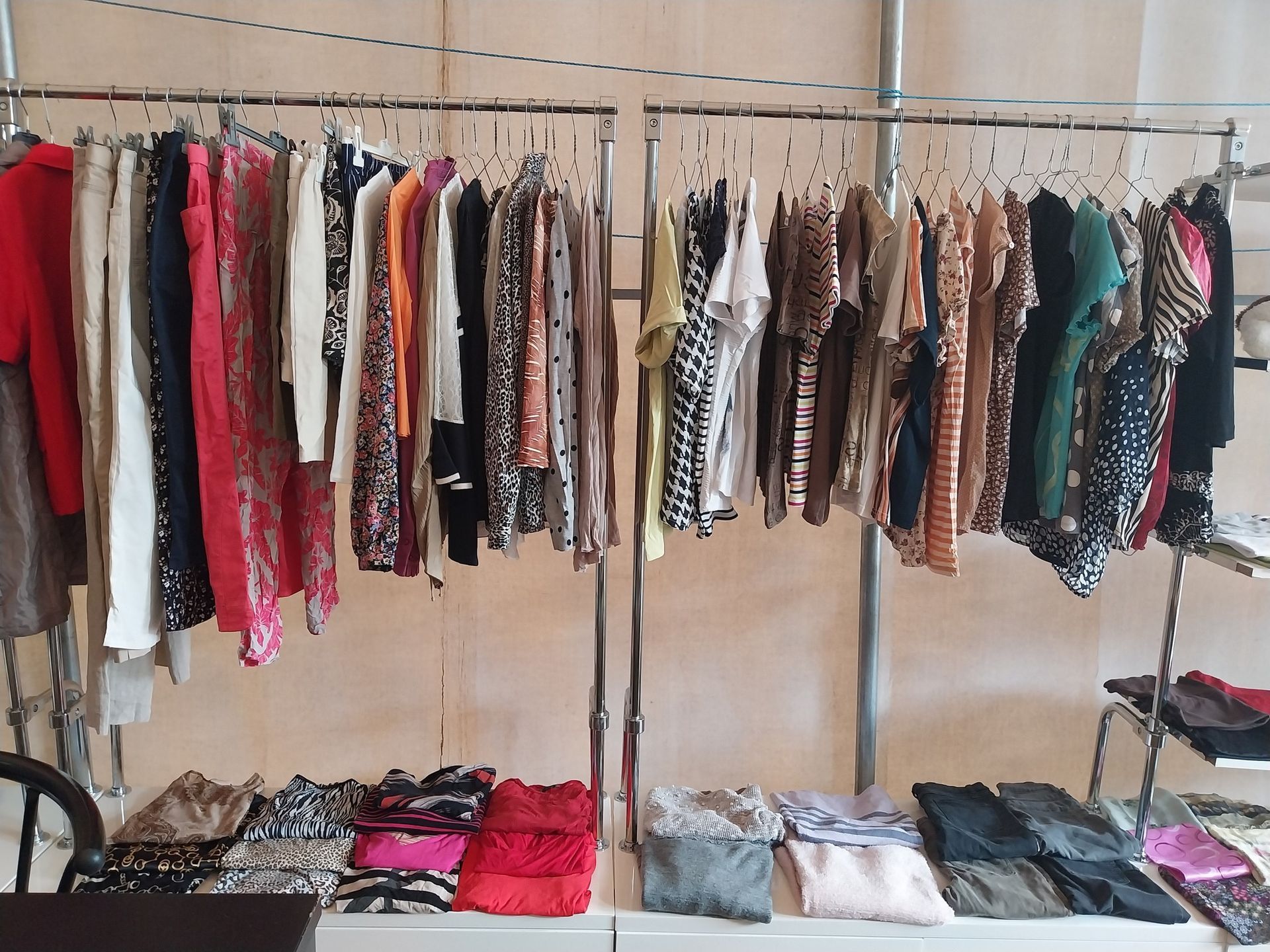 Portant à vêtements avec divers vêtements sur cintres et pliés en dessous.