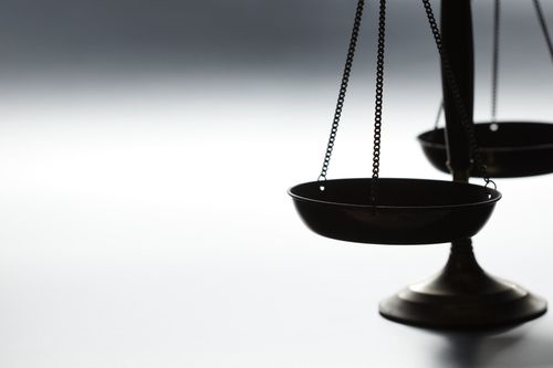 Gros plan sur une balance noire en équilibre sur fond blanc