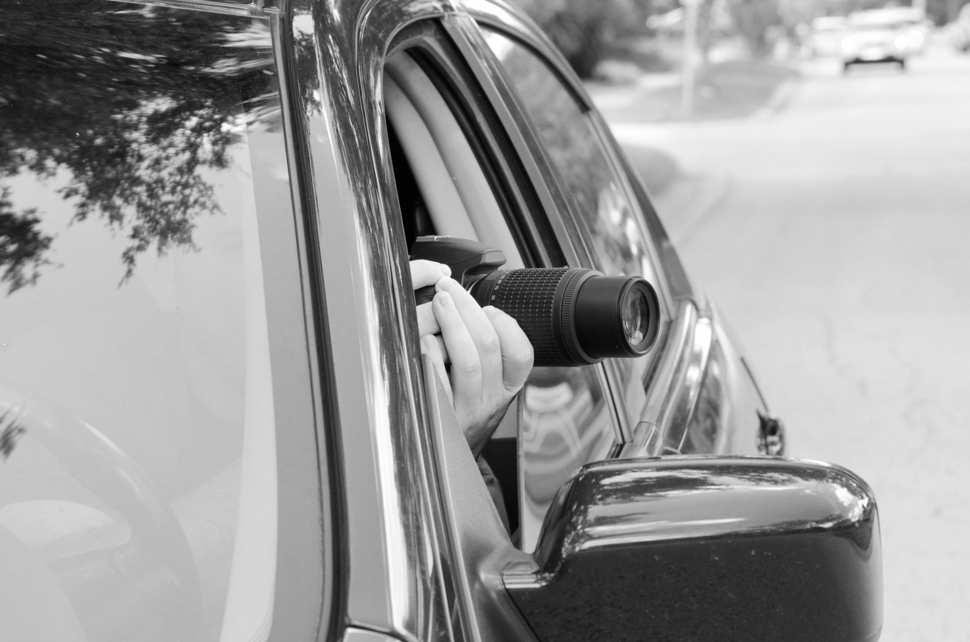 Une personne pointe un appareil photo par la fenêtre d'une voiture en direction de la route.