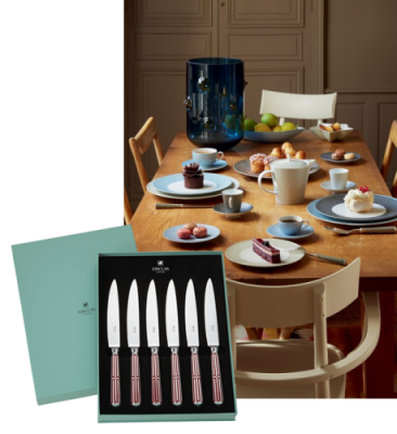 Six couteaux à steak dans une boîte, disposés sur une table dressée pour le repas.
