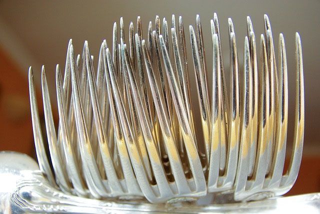 Gros plan sur un arrangement de fourchettes en argent, dents vers le haut, dans un support décoratif.