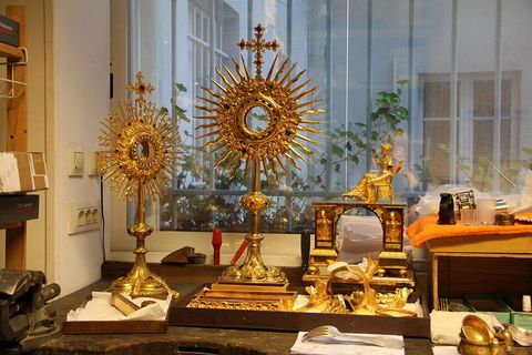 Deux ostensoirs dorés richement décorés et un tabernacle sur un établi.