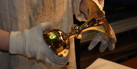 Personne portant des gants et tenant un élément de trophée doré et brillant.