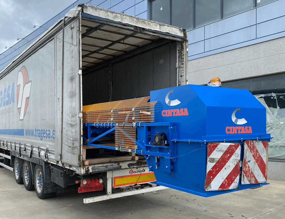 Un camión con la puerta trasera abierta transporta un gran objeto azul.