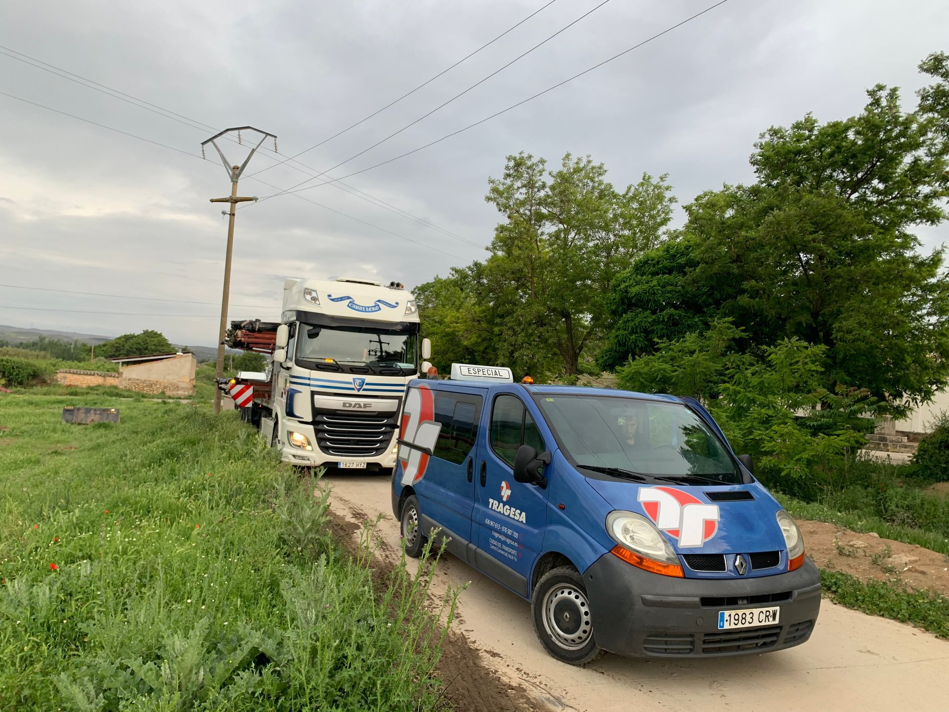 Una camioneta azul está estacionada junto a un camión en un camino de tierra.