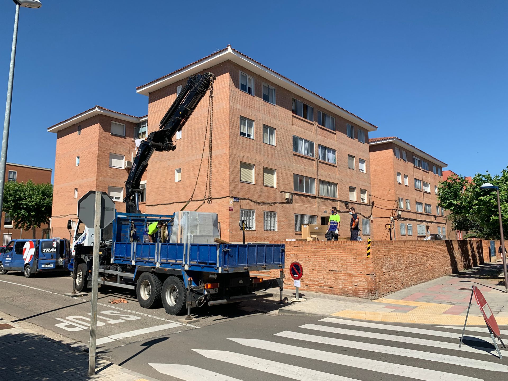 Un camión azul está estacionado frente a un gran edificio de ladrillos.
