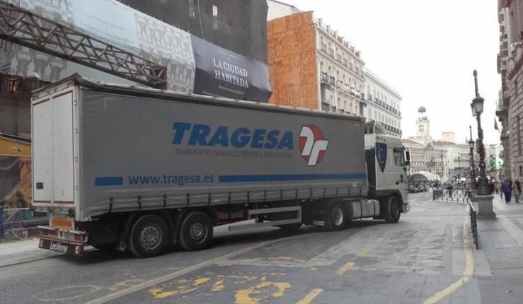 Un camión blanco con la palabra tragedia en el costado circula por una calle de la ciudad.